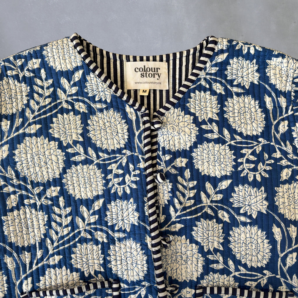 A close-up of a blue and cream floral printed garment with a striped inner collar and a visible neck label reading 'colour story'.