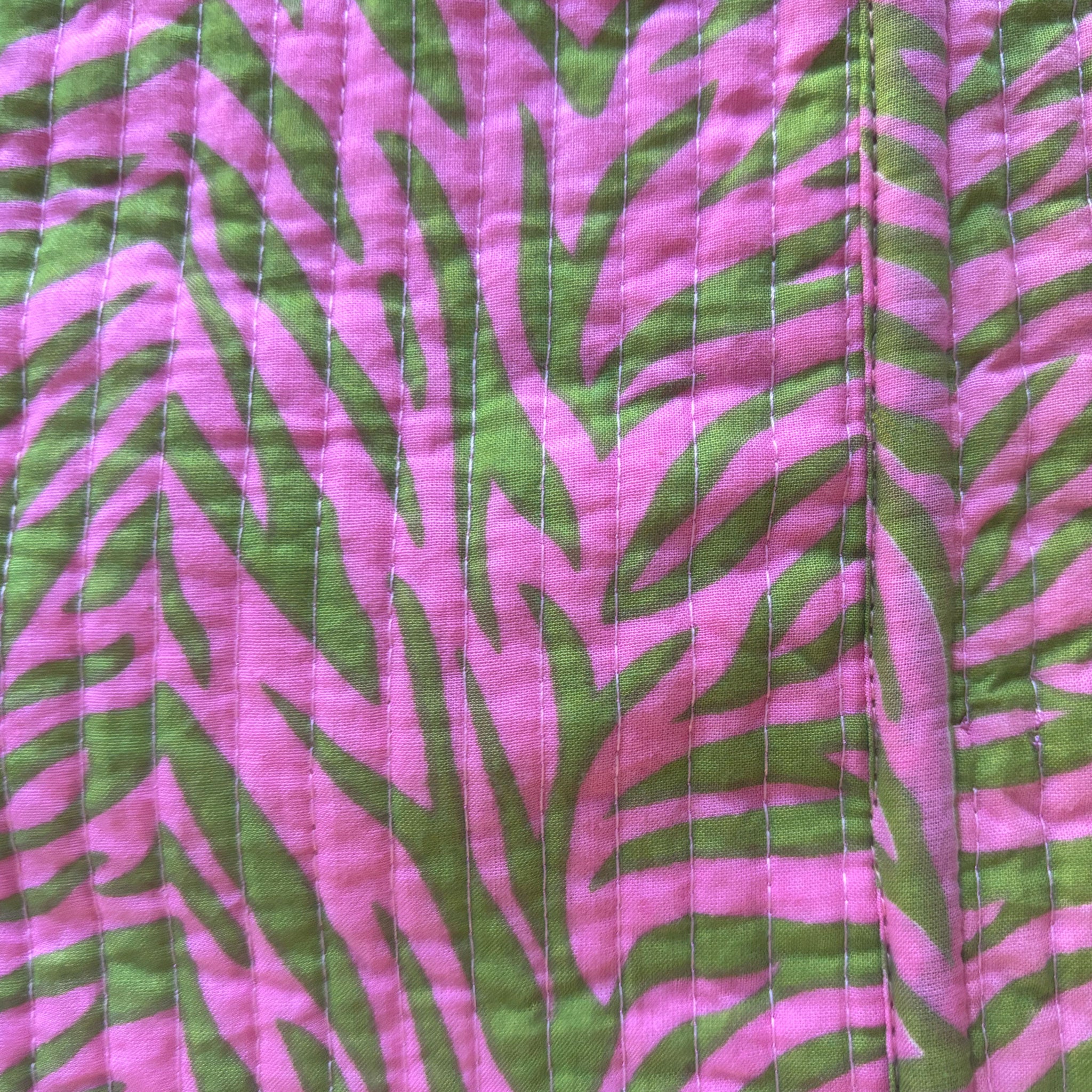 A close-up of a quilted fabric featuring a pink and green zebra pattern. This si the inside fabric of the pink Colourstory velvet jackets.