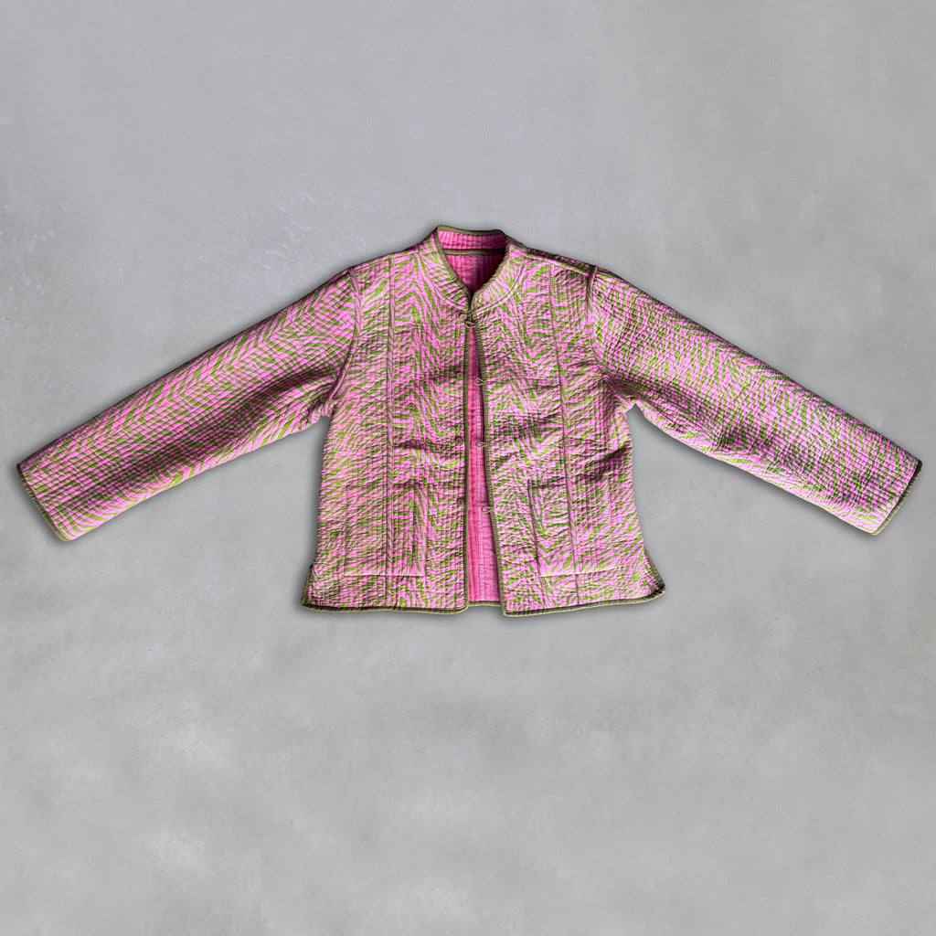 A pink quilted Colourstory jacket with a textured, zebra-like pattern in pink, green, and olive green trim laid flat on a grey background.
