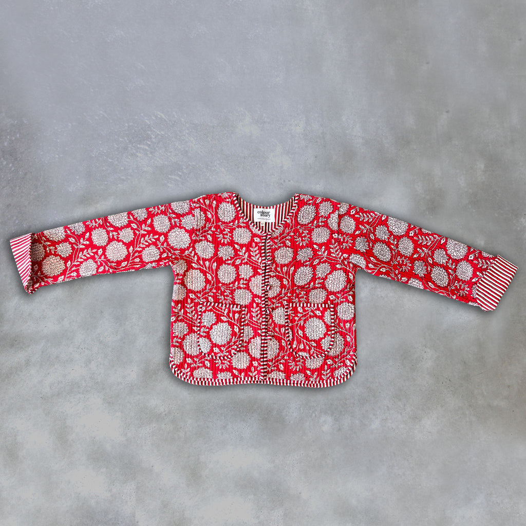 A red long-sleeve jacket by Colourstory with a white floral and circular pattern, laid flat on a textured grey background.