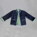 A dark navy velvet jacket with light blue piping and green-and-sage green striped cuffs, laid flat on a textured grey background.