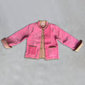 A Colourstory pink velvet jacket with olive green trim and button closures, laid flat on a grey background.