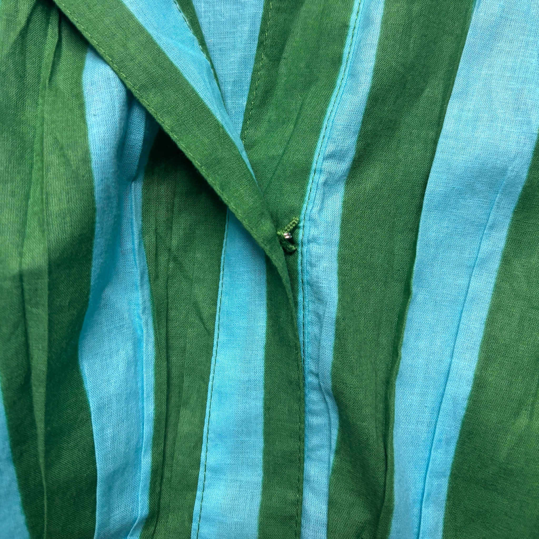Close-up of green and blue striped fabric and a hook and eye closure around the neck