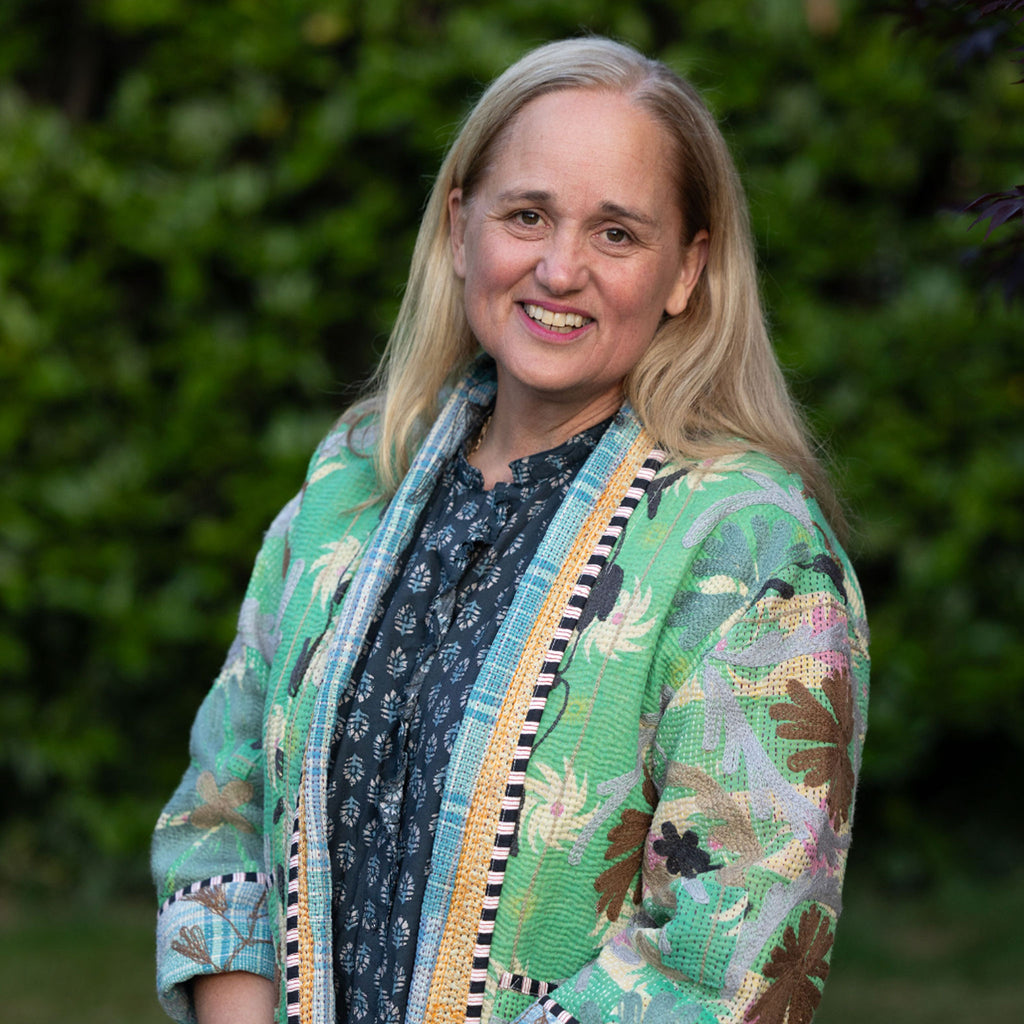 Woman (Lucy) wearing a colourful Kantha jacket with a green blurred background