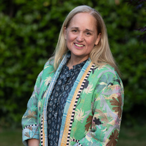 Woman (Lucy) wearing a colourful Kantha jacket with a green blurred background