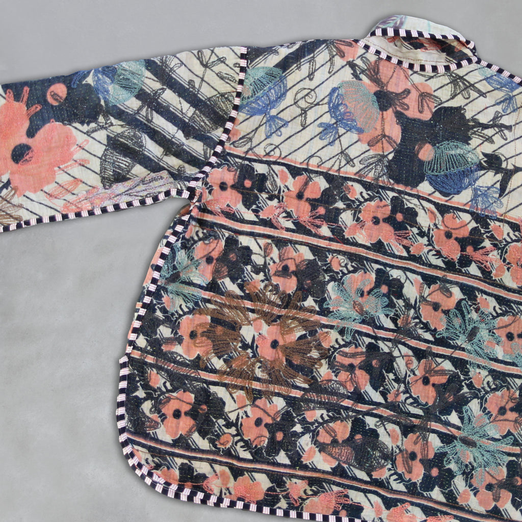 Floral and abstract patterned fabric on a Kantha jacket on grey background