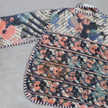 Floral and abstract patterned fabric on a Kantha jacket on grey background