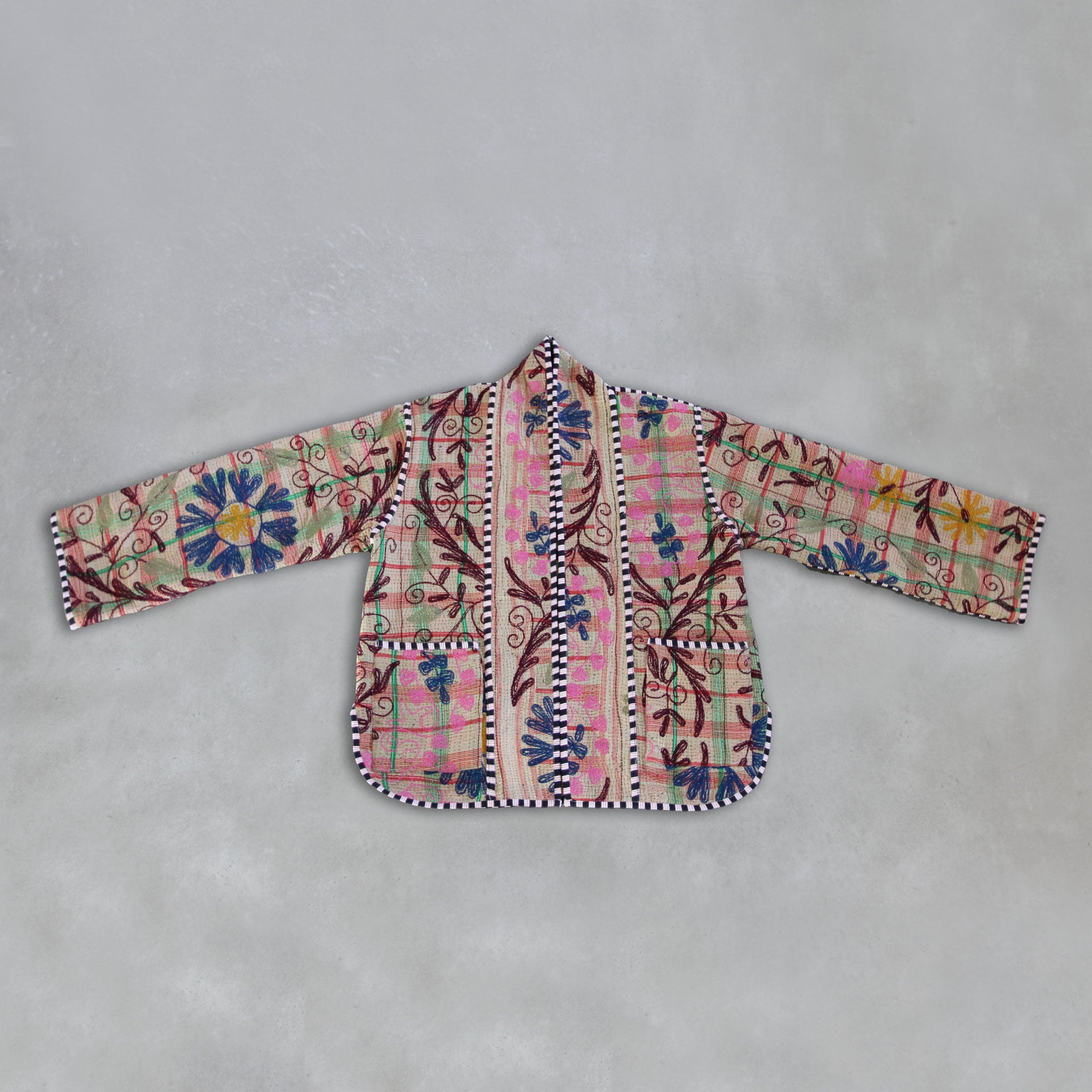 Colourful embroidered Kantha jacket on a grey background, by Colourstory.