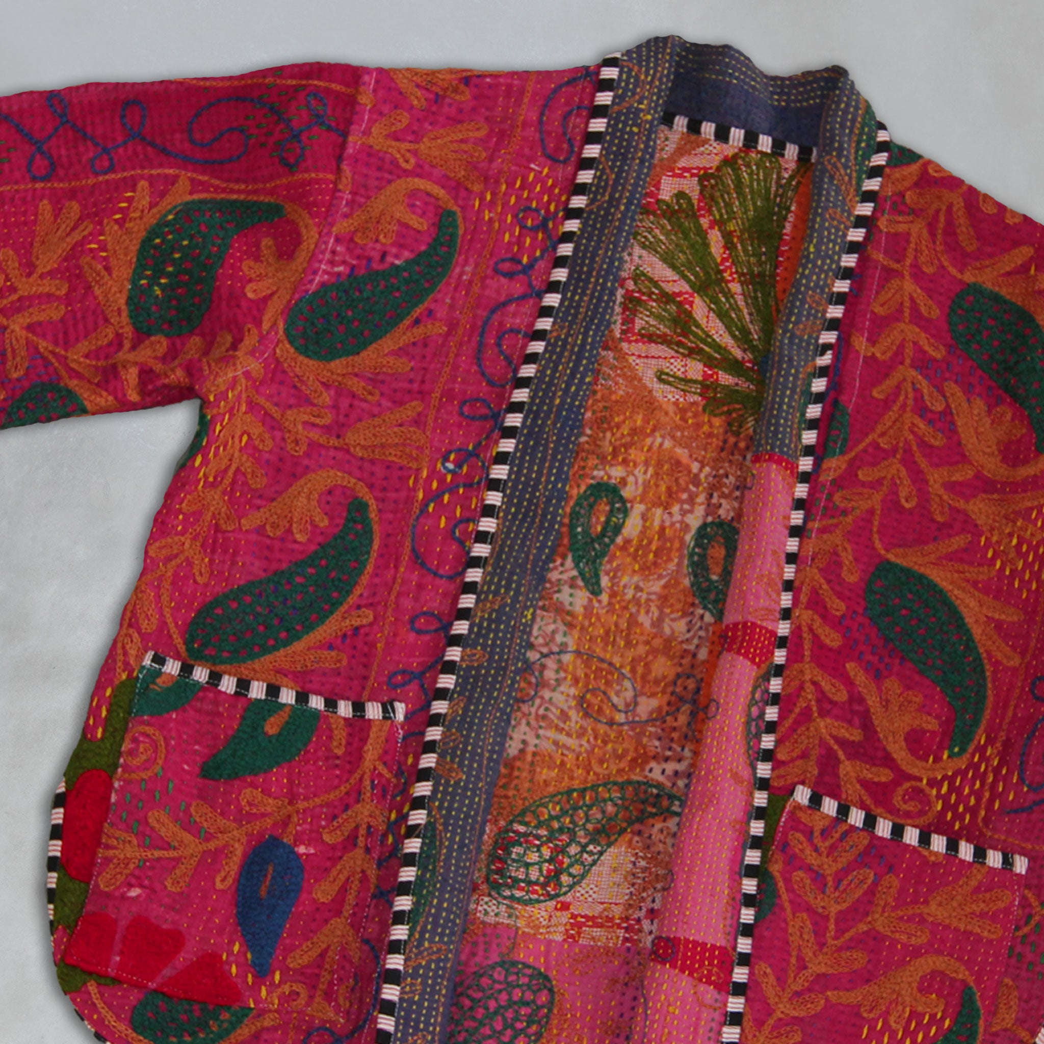 Colourful traditional Kantha jacket garment with intricate patterns on a grey background