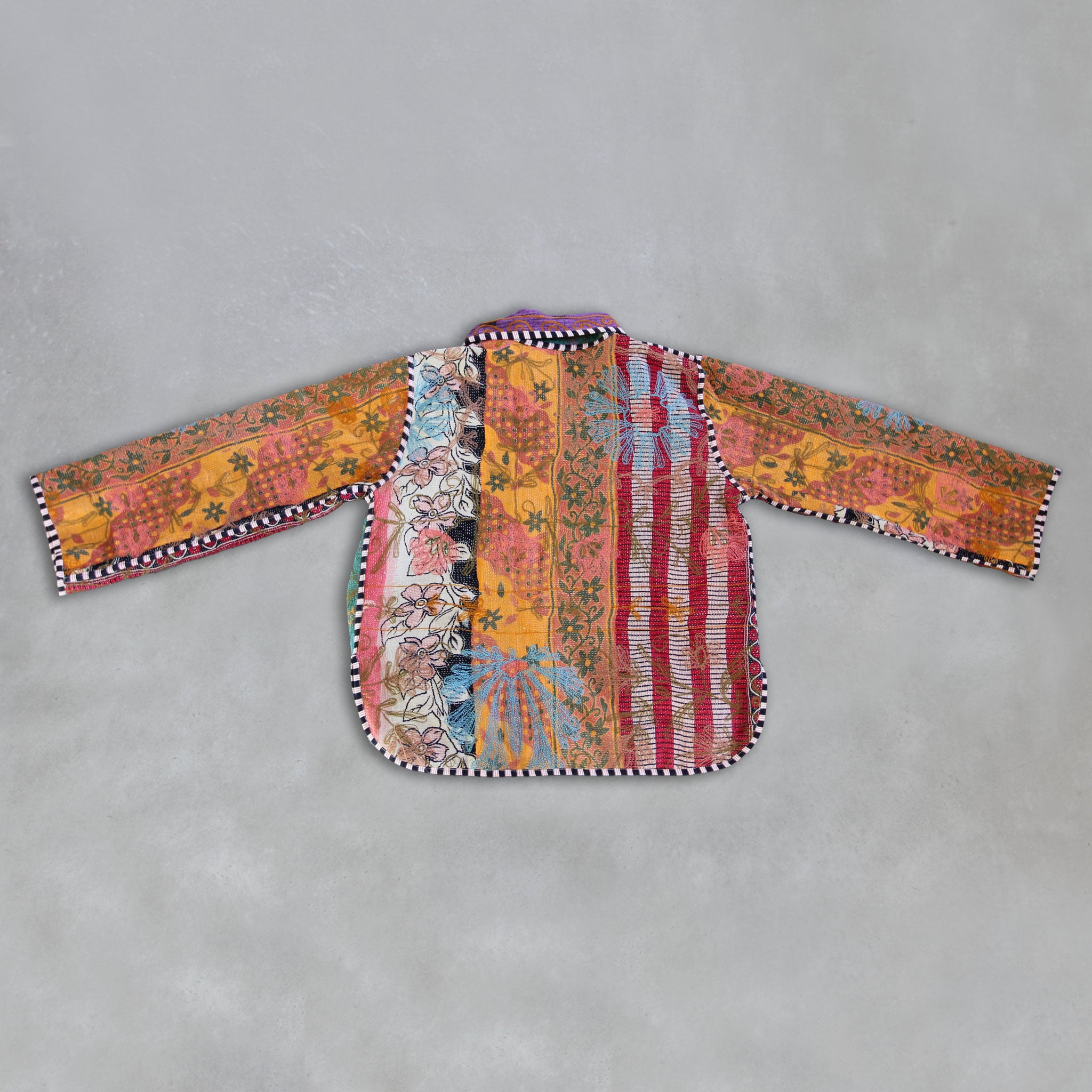 Colourful embroidered Kantha jacket on a grey background, by Colourstory.