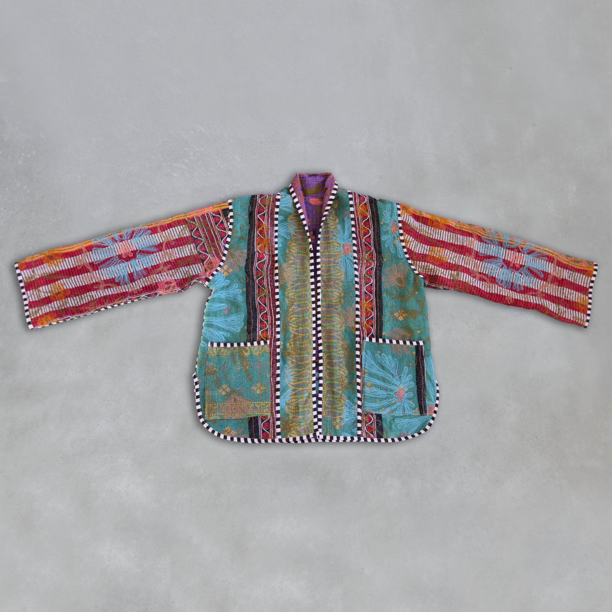 Colourful patchwork Kantha jacket on a grey background, by Colourstory.